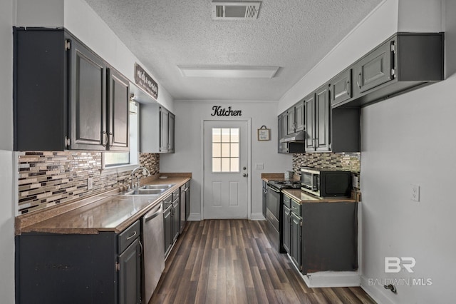 302 Norwood Ct, Bay Minette, AL 36507 - kitchen featuring stainless steel appliances, a sink, dark wood-style flooring, a textured ceiling, and tasteful backsplash