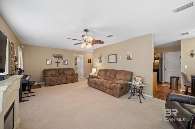 living room with a fireplace, carpet flooring, a ceiling fan, and visible vents