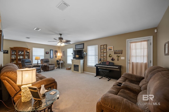 living room with visible vents, light colored carpet, baseboards, and a glass covered fireplace