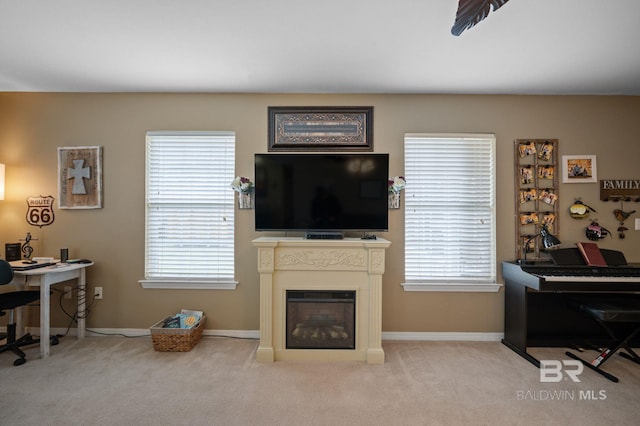 living area with carpet flooring, plenty of natural light, and a glass covered fireplace