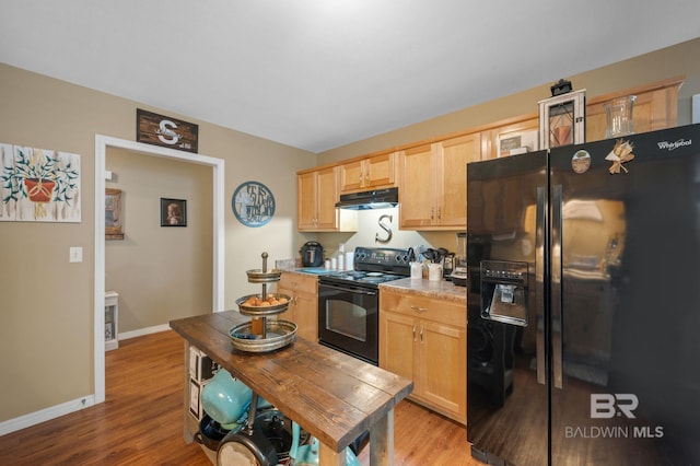 kitchen featuring under cabinet range hood, black appliances, light brown cabinetry, and light wood finished floors