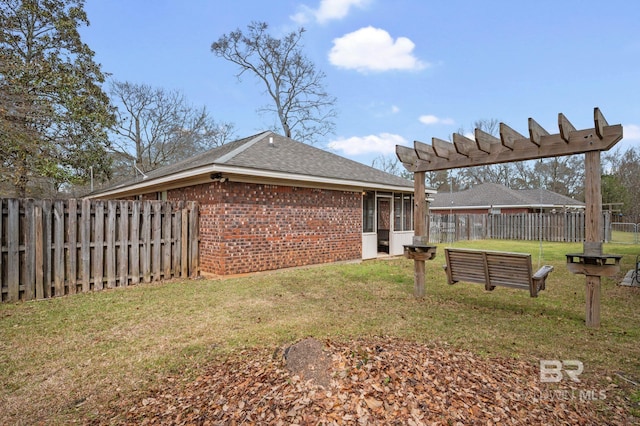 rear view of property featuring brick siding, a lawn, a shingled roof, and a fenced backyard