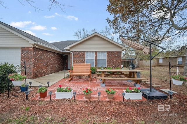 exterior space with brick siding, a patio area, an attached garage, and fence