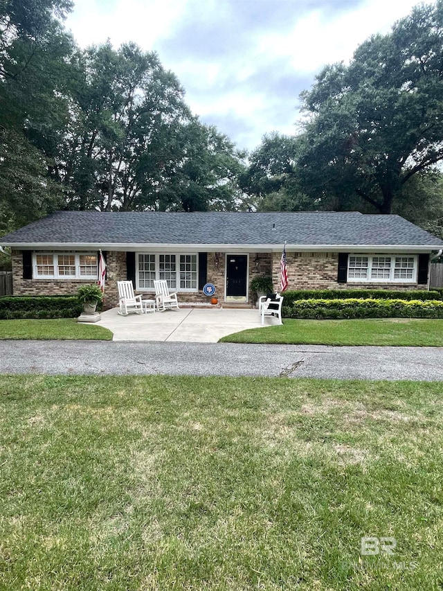 ranch-style home with a front lawn and a patio