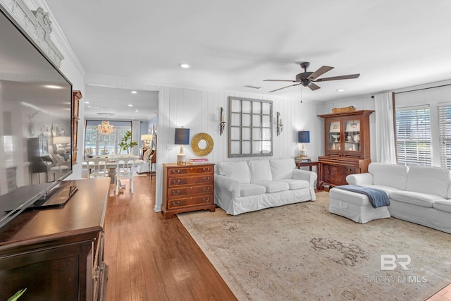 living room with wood-type flooring, crown molding, ceiling fan, and a healthy amount of sunlight