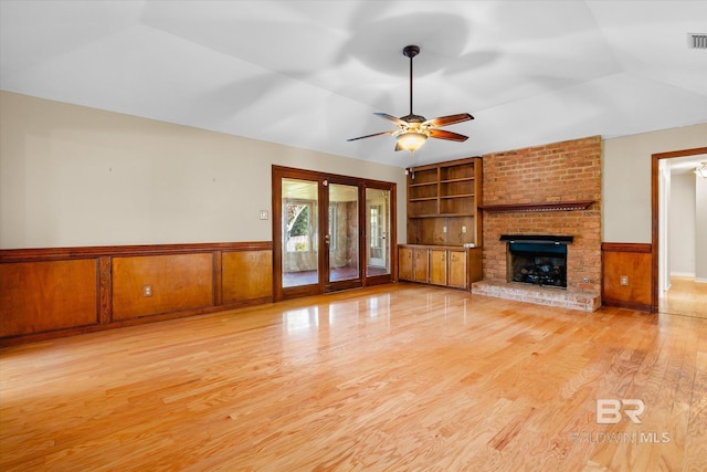 unfurnished living room featuring light hardwood / wood-style floors, built in features, and wooden walls