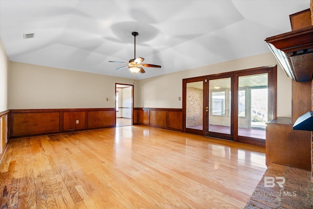 interior space featuring wood walls, ceiling fan, light hardwood / wood-style floors, and lofted ceiling