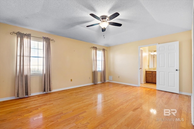 unfurnished bedroom with ensuite bath, ceiling fan, light hardwood / wood-style floors, and a textured ceiling