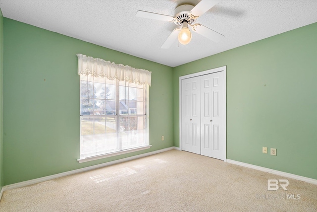 unfurnished bedroom featuring a textured ceiling, a closet, ceiling fan, and light colored carpet