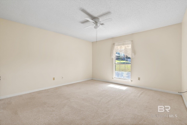 spare room featuring ceiling fan, light colored carpet, and a textured ceiling