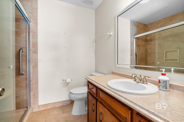 bathroom with tile patterned floors, walk in shower, vanity, a textured ceiling, and toilet