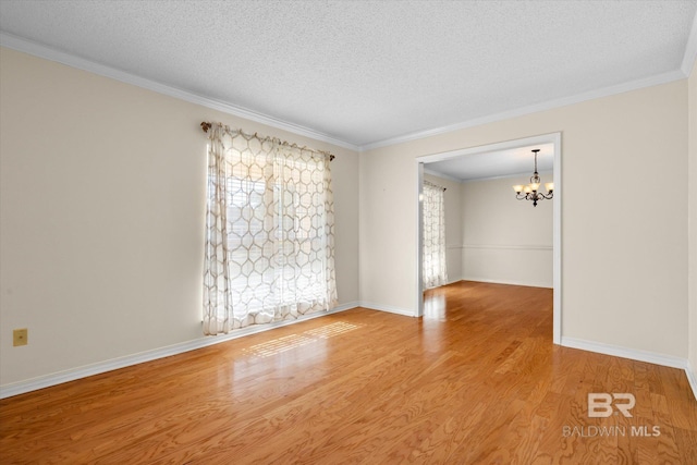 empty room with a textured ceiling, an inviting chandelier, and light hardwood / wood-style flooring