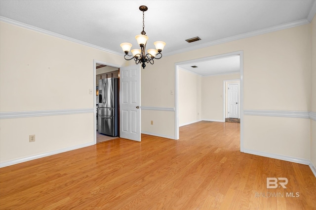 empty room with light hardwood / wood-style floors, crown molding, and a chandelier