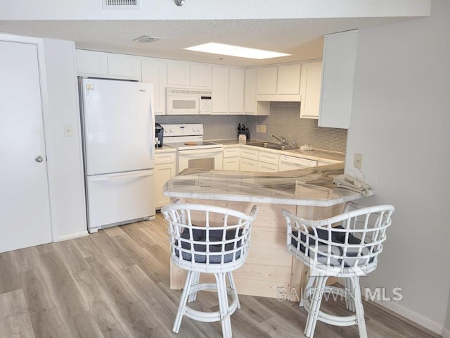 24250 Perdido Beach Blvd Unit 4603, Orange Beach, AL 36561 - kitchen with white appliances, light wood-style flooring, a peninsula, decorative backsplash, and a kitchen breakfast bar