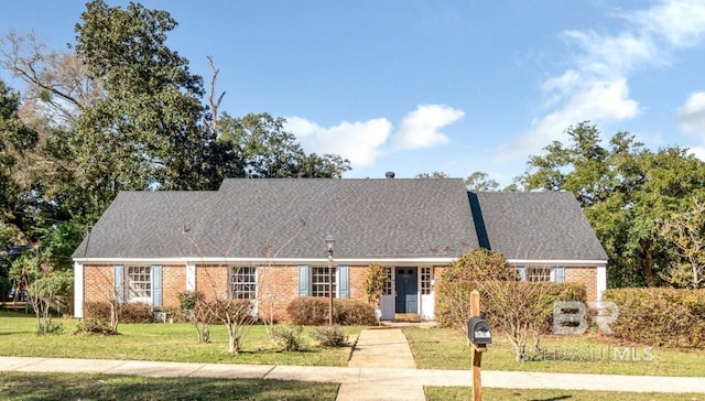 view of front of house featuring brick siding, a front lawn, and roof with shingles