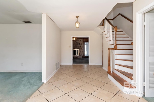 foyer featuring stairs, light tile patterned flooring, a fireplace, and visible vents