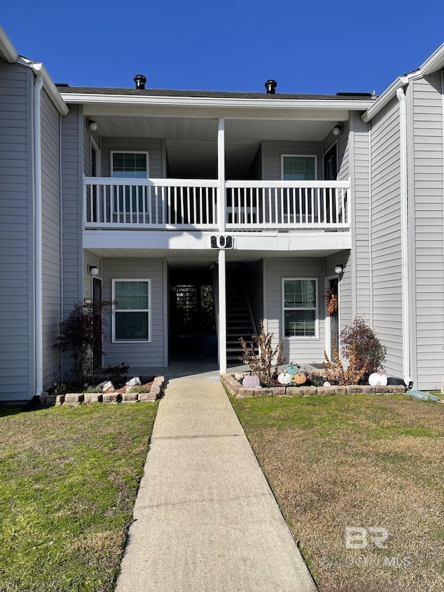 view of front of home with a balcony and a front lawn