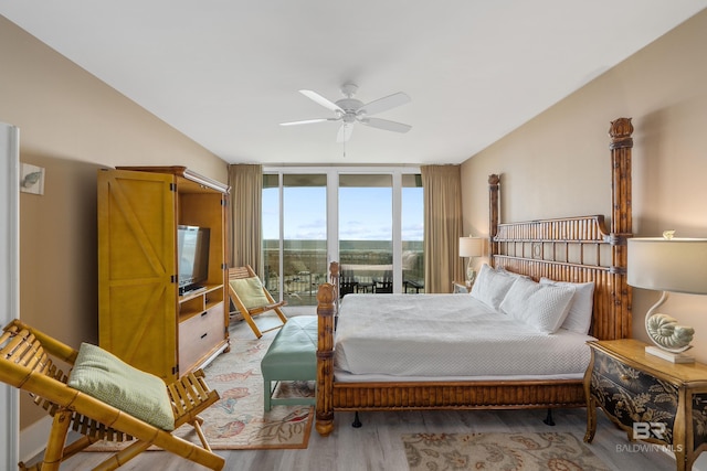 bedroom featuring a wall of windows, access to exterior, light wood-type flooring, and ceiling fan