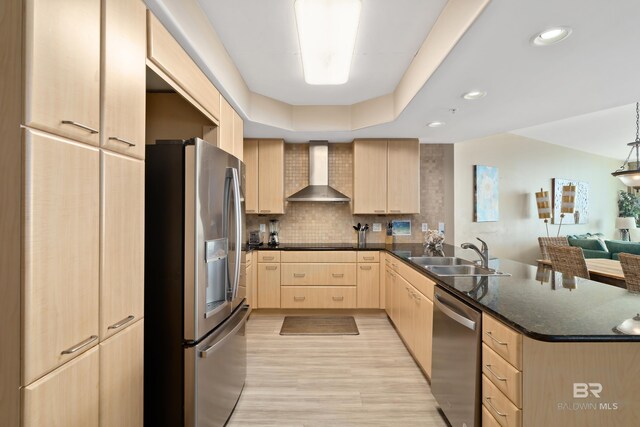 kitchen featuring light brown cabinets, light wood-type flooring, sink, wall chimney exhaust hood, and stainless steel appliances