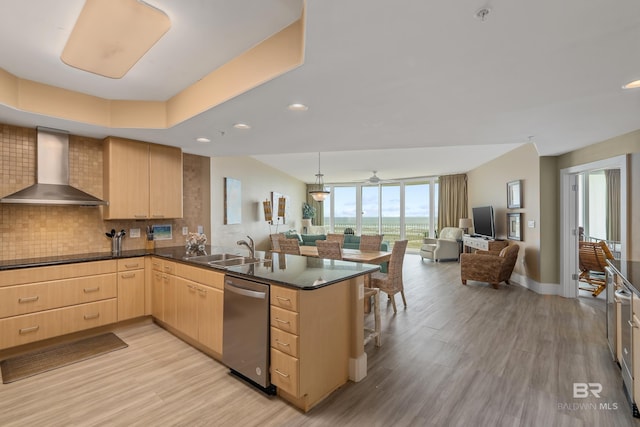 kitchen featuring wall chimney range hood, sink, dishwasher, kitchen peninsula, and light brown cabinets