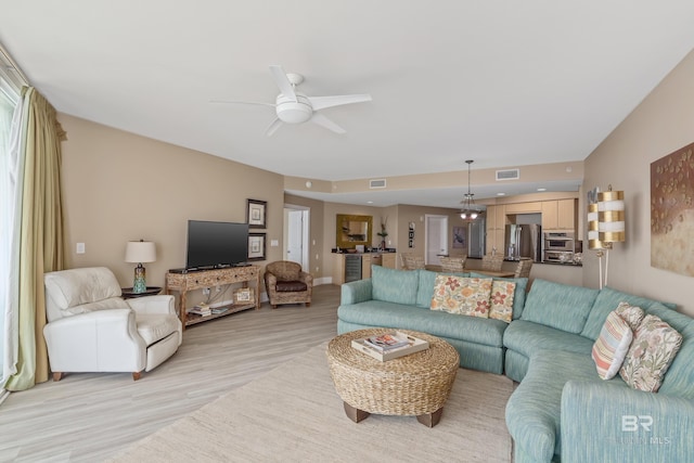 living room with ceiling fan and light hardwood / wood-style flooring