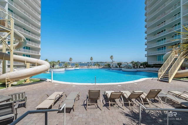 view of pool with a water slide and a patio area