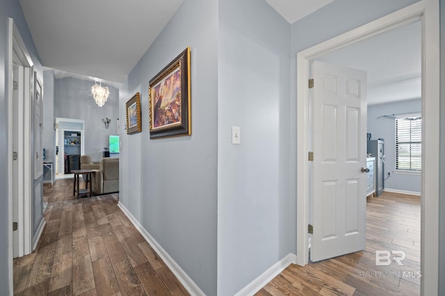 corridor featuring a notable chandelier and hardwood / wood-style flooring