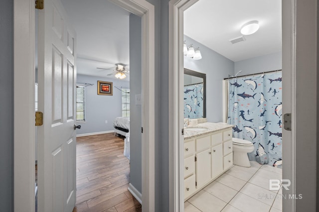 bathroom with toilet, hardwood / wood-style floors, vanity, curtained shower, and ceiling fan