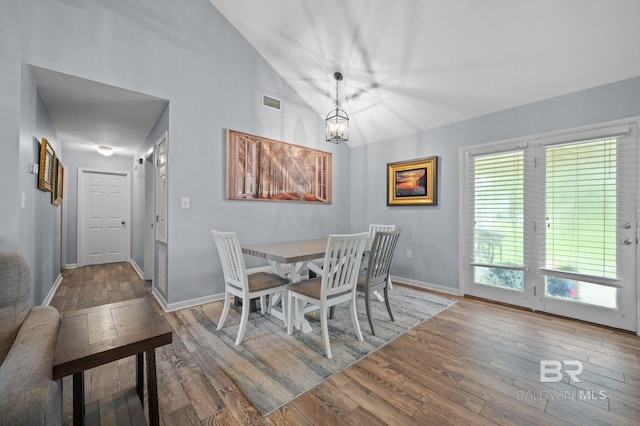 dining area featuring lofted ceiling, wood-type flooring, and an inviting chandelier