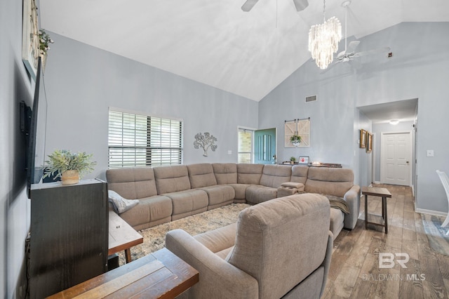 living room with ceiling fan with notable chandelier, high vaulted ceiling, and light hardwood / wood-style floors