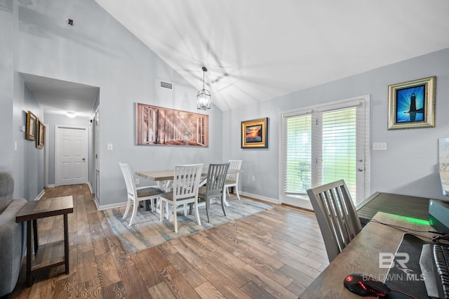 dining space with lofted ceiling, a notable chandelier, and hardwood / wood-style floors