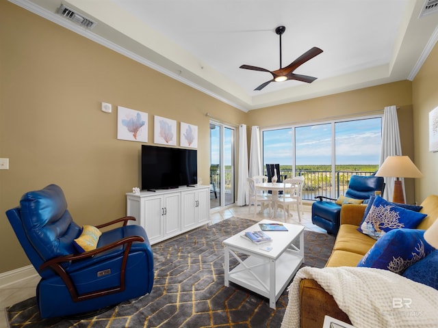 living room with a raised ceiling, a healthy amount of sunlight, and ceiling fan