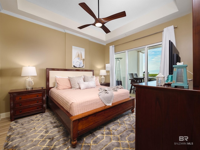 bedroom with ceiling fan, a raised ceiling, and access to outside