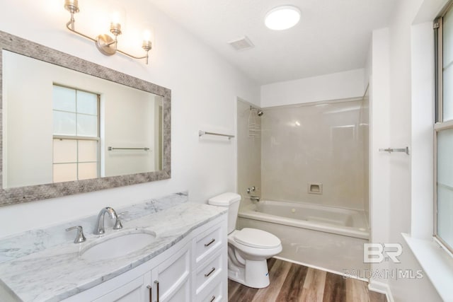 full bath with visible vents, toilet, wood finished floors, vanity, and washtub / shower combination