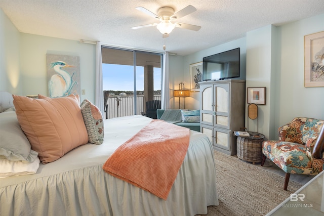 bedroom with ceiling fan, access to exterior, a textured ceiling, and expansive windows