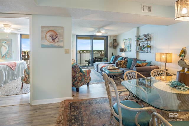 living room with a textured ceiling, ceiling fan, and hardwood / wood-style floors