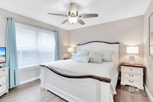 bedroom featuring ceiling fan, light hardwood / wood-style flooring, and multiple windows