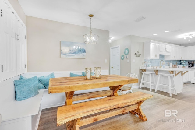 dining room with sink, a chandelier, and light wood-type flooring