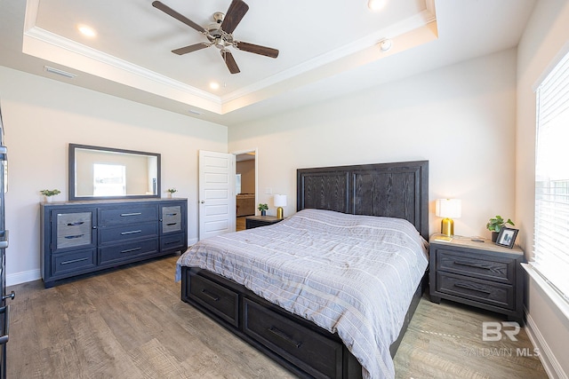 bedroom with ceiling fan, a raised ceiling, crown molding, and light hardwood / wood-style flooring