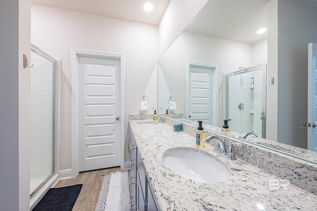 bathroom with hardwood / wood-style floors, a shower with shower door, and vanity