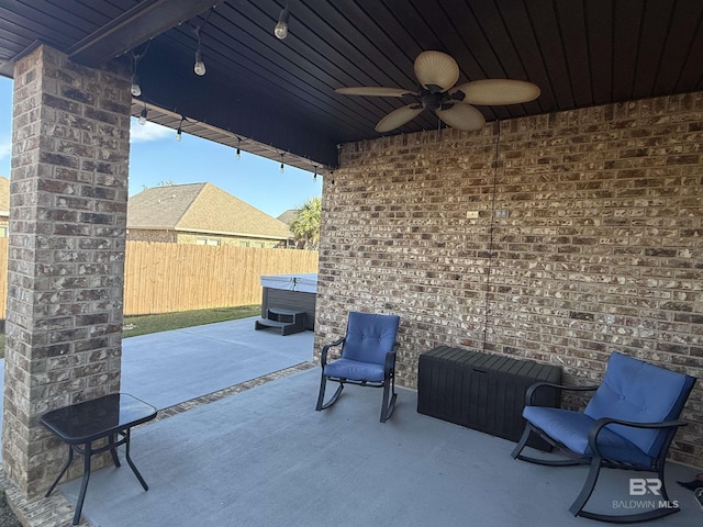 view of patio / terrace with a ceiling fan, fence, and a hot tub