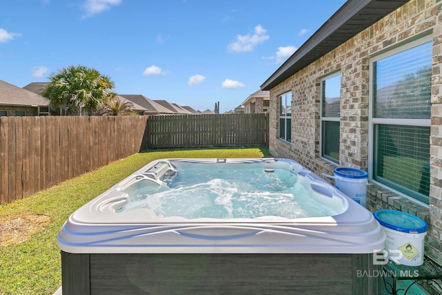 view of swimming pool featuring a yard, fence, and a hot tub