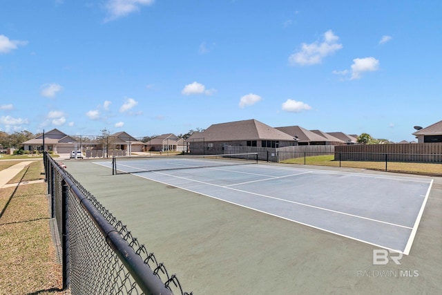 view of tennis court featuring fence and a residential view