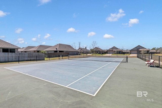 view of tennis court featuring a residential view and fence