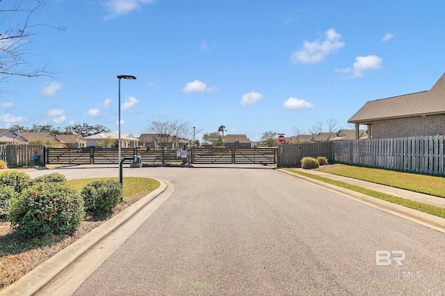 view of road featuring sidewalks, traffic signs, a gated entry, and a residential view