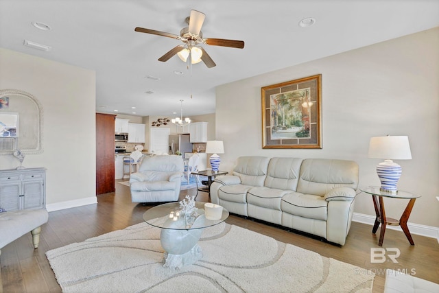 living room featuring recessed lighting, baseboards, wood finished floors, and ceiling fan with notable chandelier