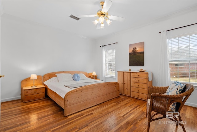 bedroom with wood finished floors, baseboards, a ceiling fan, and visible vents