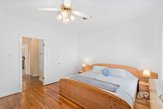 bedroom with wood finished floors, baseboards, ornamental molding, and a ceiling fan