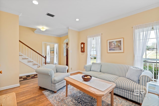 living area featuring baseboards, ornamental molding, visible vents, and light wood finished floors