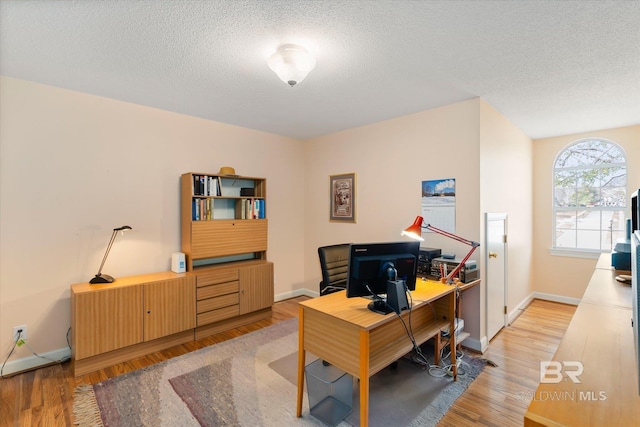 office with light wood-style floors, a textured ceiling, and baseboards